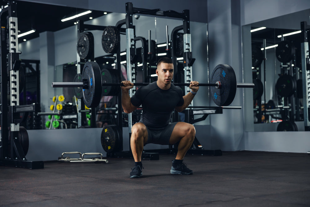 Mann macht Squats mit Langhantel im Fitnessstudio
