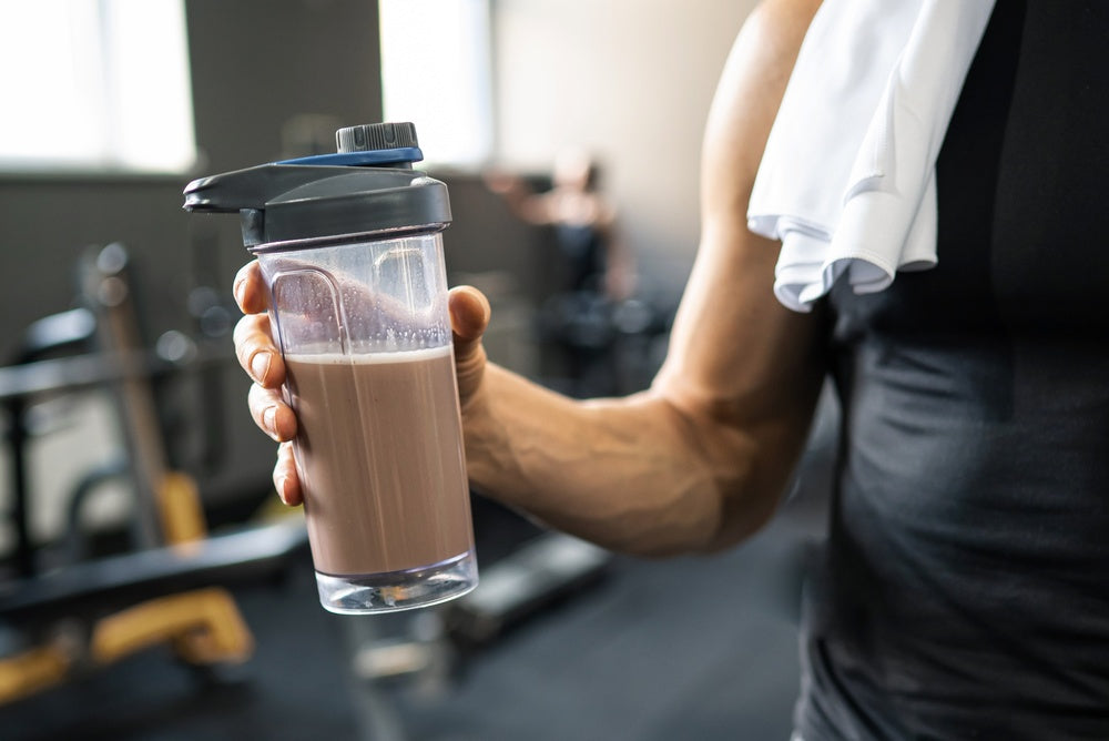 Mann trinkt Proteinpulver im Fitnessstudio
