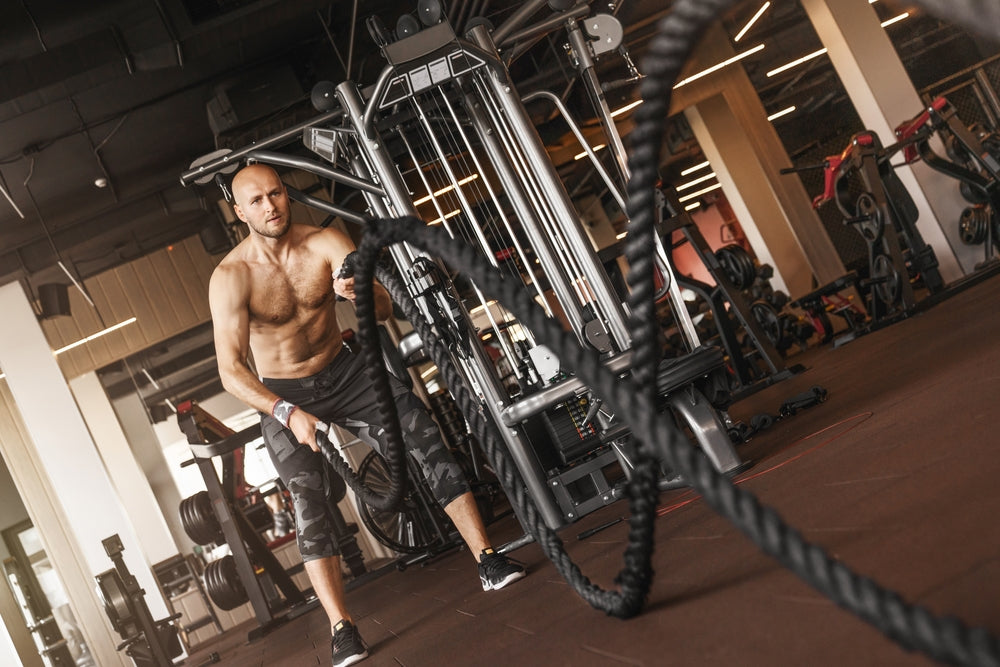 Mann trainiert mit Power Ropes und hat Motivation im Fitnessstudio