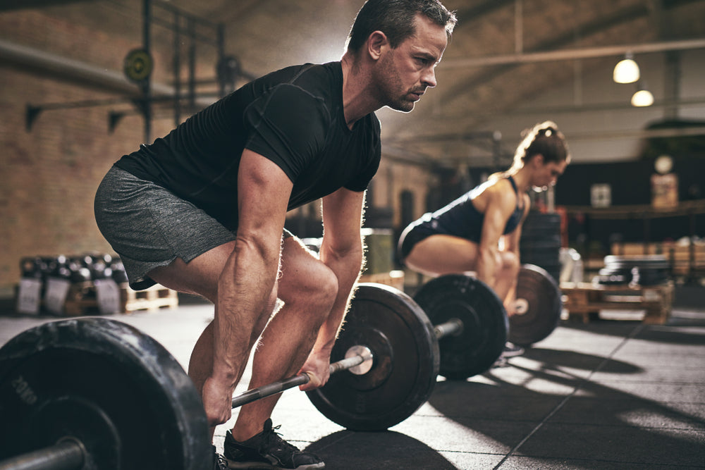 Mann und Frau trainieren Deadlifts im Fitnessstudio